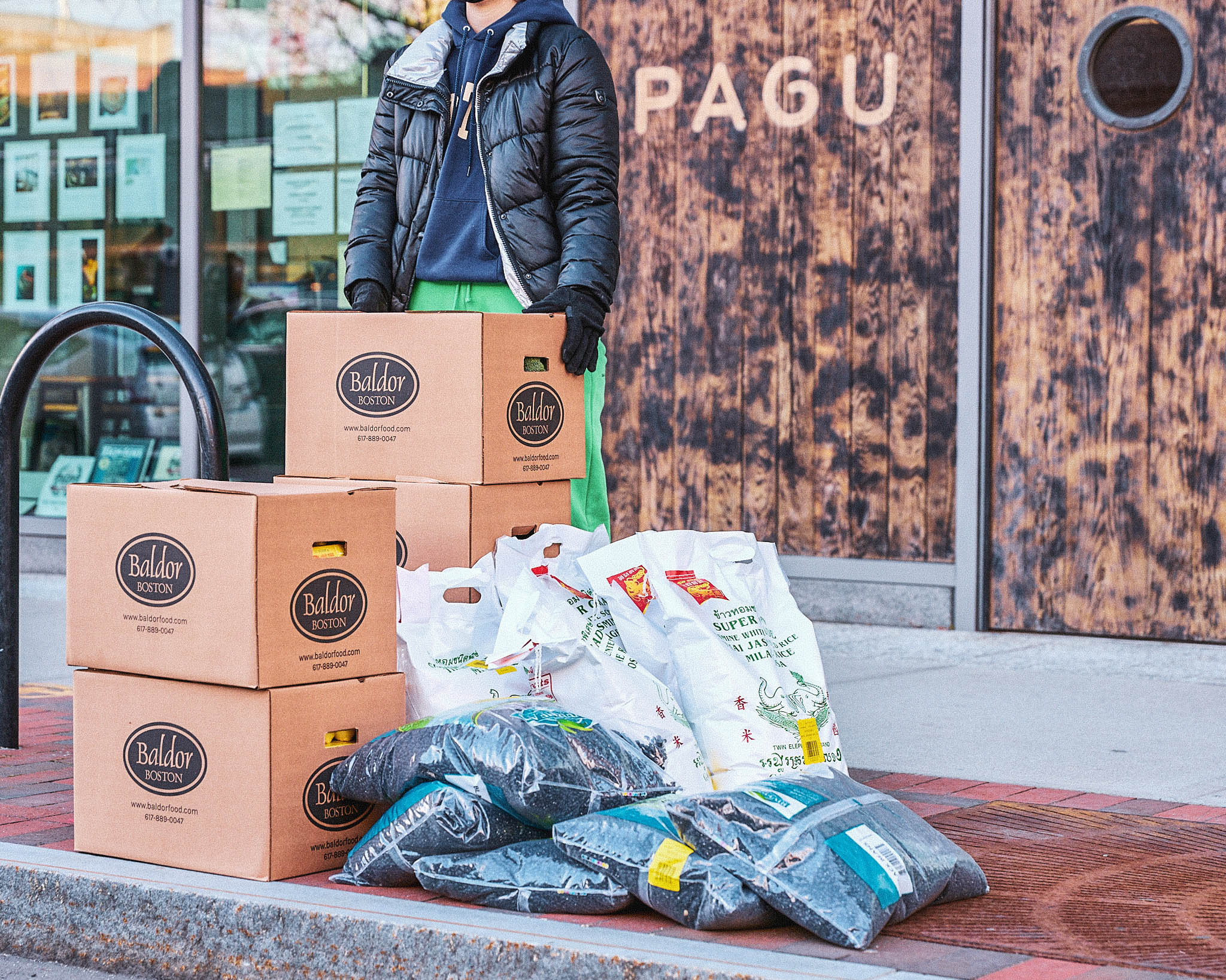 A donor waits outside of a restaurant to deliver food boxes